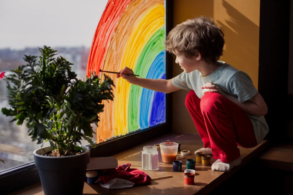 a child painting a rainbow on a window